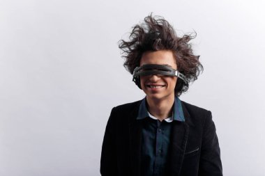 Harika kıvırcık saçlı, kulaklığı gözlerine takan, beyaz arka planda müzik dinleyen komik bir genç. Metin için boşluk.