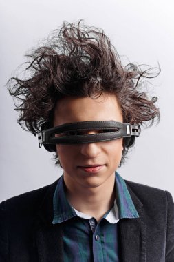 Dikey görünüm. Harika kıvırcık saçlı, kulaklık takan, beyaz arka planda müzik dinleyen genç bir adam..