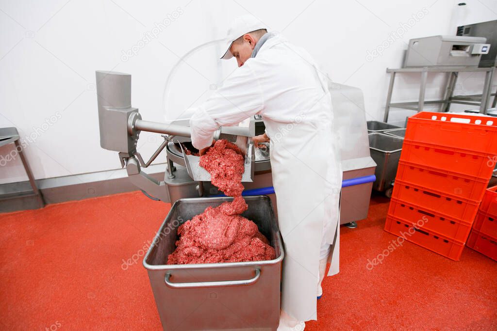 Fresh raw meat minced in an industrial process factory stored in a stainless steel crate at a processing. Horizontal view.