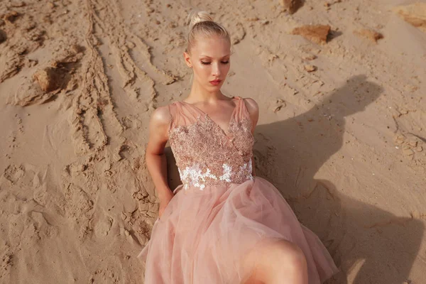 Portrait de beauté d'une belle femme blonde posant en robe de broderie sur désert, allongée sur du sable doré aux yeux fermés. — Photo