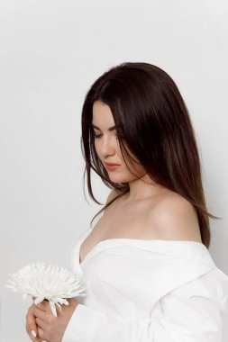 Beyaz tişörtlü, beyaz çiçekli esmer bir kadının profil portresi, beyaz bir arka planda izole edilmiş..