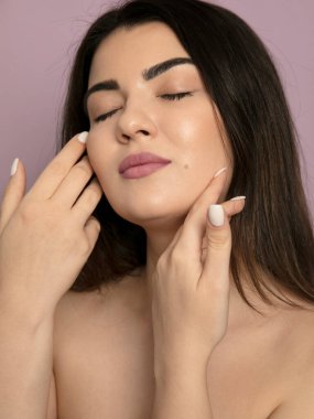 Yüzüne dokunan güzel, şehvetli bir kadının ön portresi. Güzellik ve cilt bakımı. Spa.