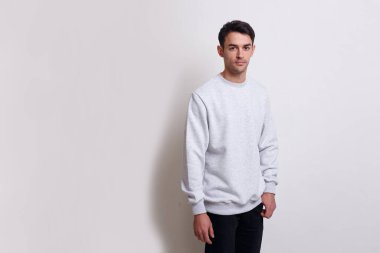 Gri kazaklı ve siyah kotlu gülümseyen esmer bir adamın önden görünüşü beyaz arka planda izole edilmiş..