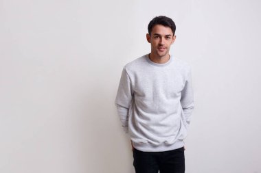 Gri kazaklı, kotlu, izole beyaz arka planlı çekici bir genç adam..