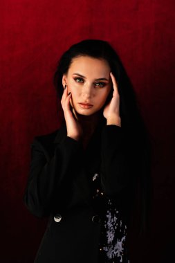 Güzel şehvet, zarif esmer kadın, kahverengi gözlü, kıvırcık saçlı, seksi gülümseyen dudaklı. Stüdyo portresi. Doğa romantizmi saf makyaj. Kırmızı arka plan. Güzellik saç stili.