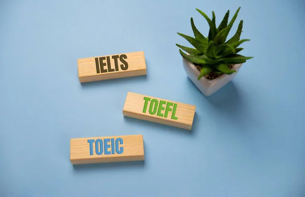 IELTS, TOEFL, TOEIC słowo na drewniane klocki na niebieskim tle — Zdjęcie stockowe