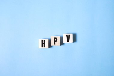 Tahta blokta HPV kelimesi yazıyor. Üst görünüm konseptiniz için mavi üzerine HPV metin.
