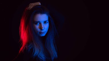 Mor stüdyo arka planında dağınık sarı saçlı seksi, çekici genç kız pembe mavi neon ışıklı gece konseptiyle tek başına dans eden şehvetli güzel kadın model..