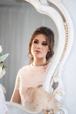 Antik aynaya, parlak makyaja ve mücevherlere bakan güzel bir kadının moda portresi..