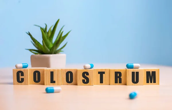 Slovo COLOSTRUM složené z dřevěných písmen na modré Stock Snímky