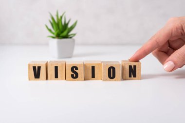 Vizyon kelimesi kadın eli olan tahta bir oyuncak blokta