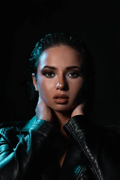 Siyah deri ceket giyen şık bir kadın. Şık ve kendine güvenen uzun kıvırcık saçlı bir kız. Kıyafet, tarz ve moda.