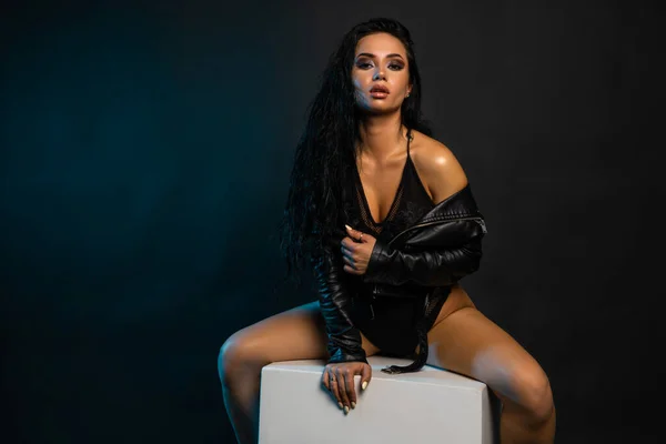 Siyah deri ceket giyen şık bir kadın. Şık ve kendine güvenen uzun kıvırcık saçlı bir kız. Kıyafet, tarz ve moda.