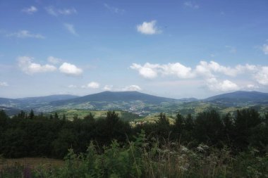 Temmuz 'da Beskids' ta, bir dağ çayırından vadiye ve tepelere, ormana, gökyüzüne ve bulutlara manzara