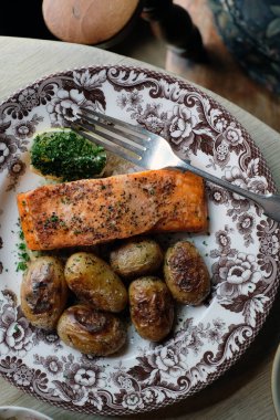 Lezzetli kızarmış somon ve yanında yeni patatesler. Eski bir tabakta servis ediliyor.