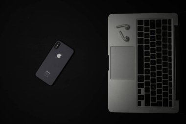 Telefon, bluetooth kulaklık ve bilgisayar laptopu siyah ahşap bir masada..