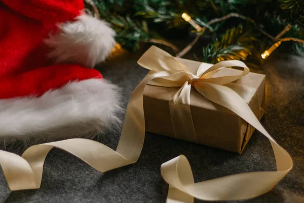 Noel Baba şapkası ve gri arka planda Noel ışıklarıyla Noel süslemeleri..