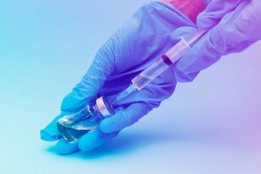 Mavi eldivenli eller şırıngayı aşı için test tüpüyle doldurur. Sağlık ve Tıp kavramı