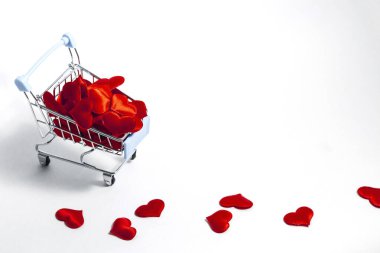 Beyaz arka planda kırmızı konfeti kalpleriyle dolu bir süpermarket arabası. Hediye alma kavramı. Boşluğu kopyala.