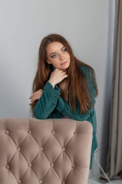 Mutlu ve başarılı bir iş kadını yeşil takım elbiseli bir sandalyeye yaslanıyor..