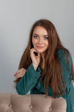 Mutlu ve başarılı bir iş kadını yeşil takım elbiseli bir sandalyeye yaslanıyor..