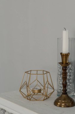 Şık dekorlu şömine rafı. Altın şamdanlı mumlar. Retro dekor.