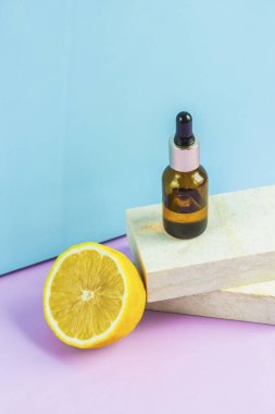 Göz damlası olan bir kozmetik kavanozu iki granit levhanın üzerinde durur, podyumlardaki gibi, yarım sarı limonun yanında. Minimalizm ve çevre dostluğu kavramı.