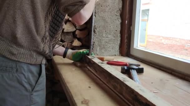 一个戴手套的人试图用指甲钳把钉子从木条上拔下来 — 图库视频影像