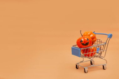 El arabasında turuncu balkabakları ve bej arka planda dağınık balkabakları. Cadılar Bayramı 'nda satıştan bahseden yassı lei. Boşluğu kopyala.