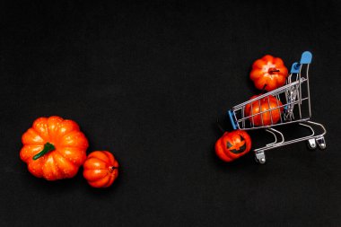 Arabadaki turuncu balkabakları ve siyah arka planda dağınık balkabakları. Cadılar Bayramı 'nda satıştan bahseden yassı lei. Boşluğu kopyala.