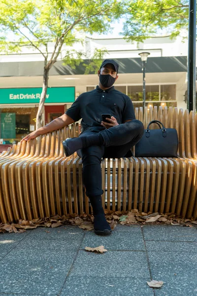 Avrupa tarzı şık kıyafetler giymiş erkek manken. Yanında bir çanta, dizüstü bilgisayar ve anahtarla bir bank ve kafede.