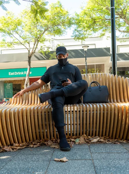 Avrupa tarzı şık kıyafetler giymiş erkek manken. Yanında bir çanta, dizüstü bilgisayar ve anahtarla bir bank ve kafede.