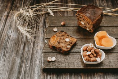 Ekmek, fındık, kuru meyveler karanlık bir arka planda 