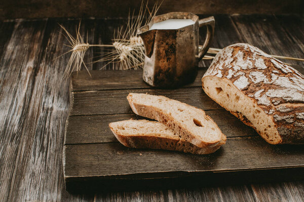 молоко и сельский хлеб на темном фоне 