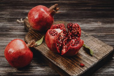  Koyu arkaplanda tahtadan bir tahtada üç kırmızı nar.