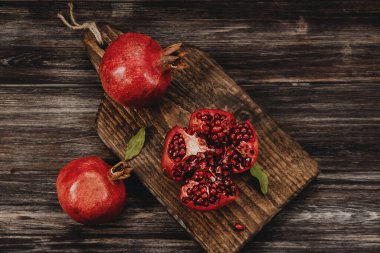 Üç kırmızı nar, ahşap bir tahtanın üzerinde, kırsal tarzda.