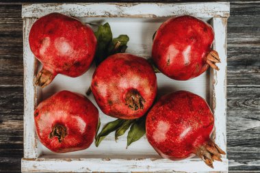 Hafif ahşap bir kutuda, üzerinde koyu bir zemin olan narlar.