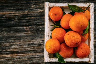 Tahta bir masanın üzerinde yaprakları olan portakallar.