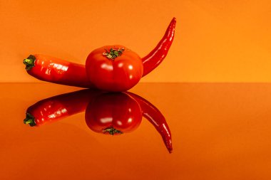 Turuncu arka planda domates ve acı biber. 