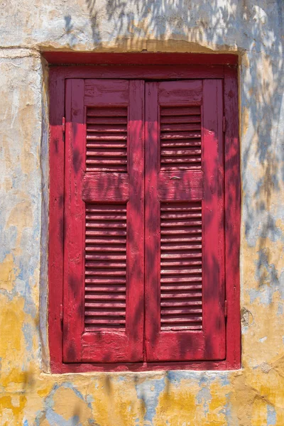 Verlichte venster met rode sluiter — Stockfoto