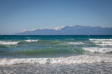 Yaz sonunda dramatik dalgalarla dolu İyon Denizi. Arkadaki Arnavut dağları. Beyaz bulutlu mavi gökyüzü. Korfu Adasının Kuzeyi (Korfu), Acharavi, Yunanistan.