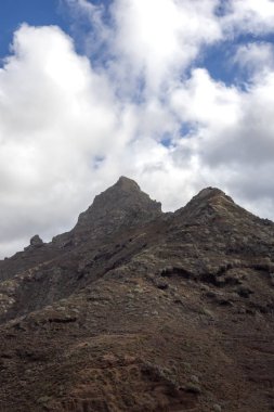 Adanın kuzeybatısındaki yüksek kıyı dağlarının ayrıntıları. Sonbaharda yoğun bulutlu mavi gökyüzü. Punta de Hidalgo, Tenerife, Kanarya Adaları, İspanya.