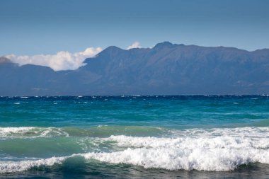 Yaz sonunda dramatik dalgalarla dolu İyon Denizi. Arkadaki Arnavut dağları. Beyaz bulutlu mavi gökyüzü. Korfu Adasının Kuzeyi (Korfu), Acharavi, Yunanistan.