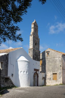 Taş kulesi olan tarihi kilise, çan kulesi. Bir köyde sokak. Parlak mavi gökyüzü. Makratika, Paxos, Yunanistan.