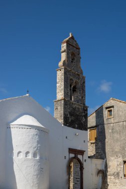 Taş kulesi olan tarihi kilise, çan kulesi. Bir köyde sokak. Parlak mavi gökyüzü. Makratika, Paxos, Yunanistan.