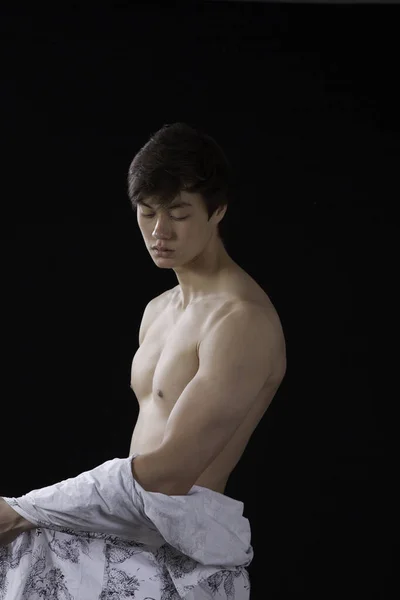 Düşünceli genç adam gömleğini çıkarmış.