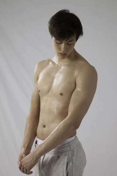 Tişörtsüz genç adam düşünceli görünüyor.