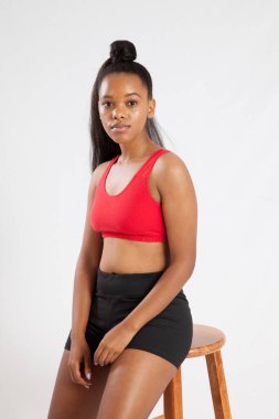 Düşünceli siyah kadın bir taburede dinleniyor.