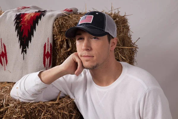 Düşünceli kovboy elinde bir saman balyasıyla oturuyor