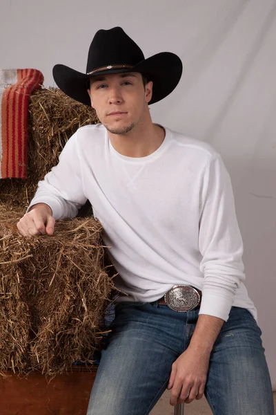 Düşünceli kovboy elinde bir saman balyasıyla oturuyor